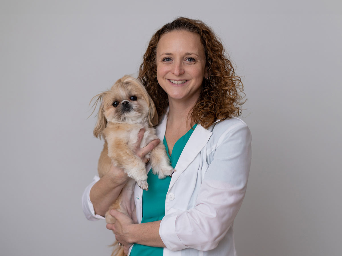 Dr. Casey Havemann smiling and looking at the camera while holding small dog